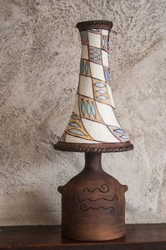 a lamp that is sitting on top of a wooden shelf in front of a stone wall