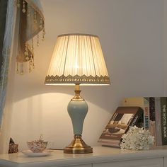 a lamp sitting on top of a white table next to a book shelf with books