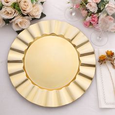 a white table topped with a gold plate and flowers