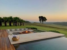 an outdoor fire pit on top of a wooden deck next to a large swimming pool