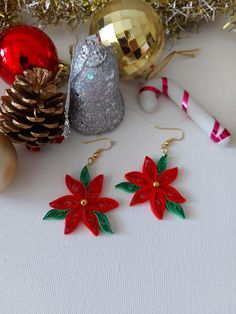 two red poinsettias are sitting next to some christmas decorations and a pine cone