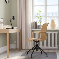 a room with a desk, chair and clock on the wall next to a window