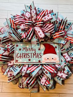 a christmas wreath on the floor with santa clause's hat and red white and blue ribbons