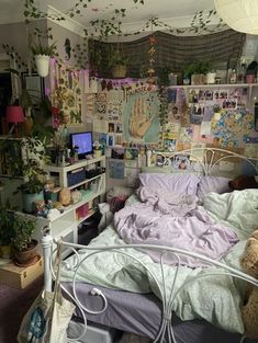 a messy bedroom with lots of plants and pictures on the wall above the bedspread