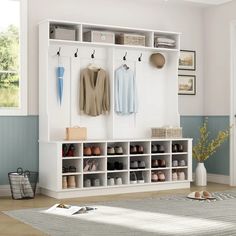 a white coat rack filled with shoes next to a rug and wall mounted shelf unit