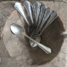 spoons and forks are sitting on a stone plate