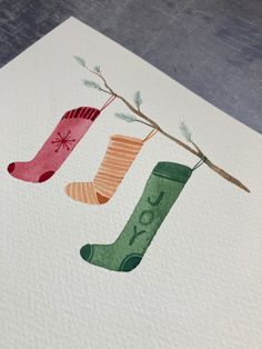 three socks hanging from a tree branch on paper