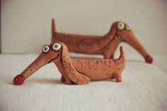 two clay dachshund figurines sitting on top of a bed