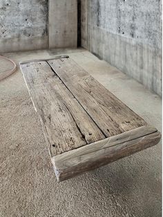 a wooden table sitting on top of a carpeted floor next to a concrete wall