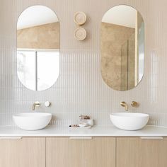 two white bowls are sitting on the counter in front of three round mirrors that hang above them