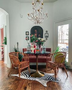 An eclectic display of quirky accessories is perfect for this oddly-shaped room.  A faux zebra rug lays beneath a pedestal table, creating a defined area for a small maroon bench and rattan chairs. The lighting features an intricate chandelier with white beaded embellishments on all the curves...   Image: indigoleopardhome