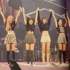 the girls are performing on stage with their hands in the air