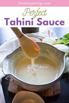 the sauce is being poured in a pot with a wooden spoon and white flowers behind it