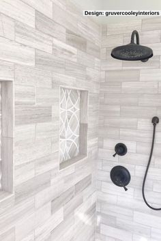 a shower head and hand shower in a white tiled bathroom with black fixtures on the wall