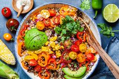 a bowl filled with rice and vegetables next to corn on the cob, avocado