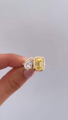 someone is holding an engagement ring with a yellow and white diamond in it's middle