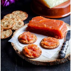 some crackers are sitting on a wooden plate with sauce and cheese in the background