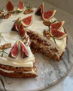 a cake with white frosting and sliced figs on the top is sitting on a marble platter