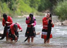 three women in red and black outfits standing in water