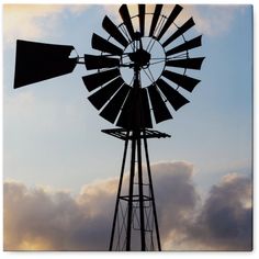 the silhouette of a windmill against a cloudy sky