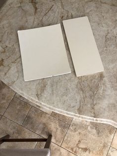 two pieces of white paper sitting on top of a marble counter next to a chair