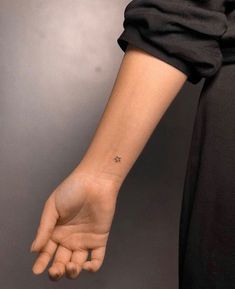 a woman's arm with a small star tattoo on the left side of her wrist