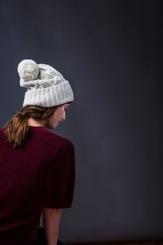 a woman wearing a white knit hat with pom - poms on her head