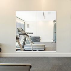 a gym with treadmills, exercise machine and mirror in the wall behind it