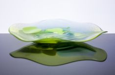 a green glass bowl sitting on top of a table