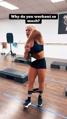 a woman in black shorts and knee high socks standing on a wooden floor with an exercise mat