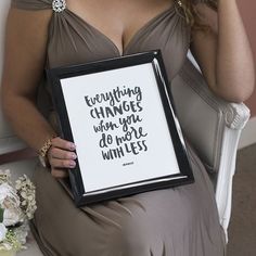 a woman in a dress holding up a framed sign with the words everything changes when you do not win less