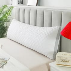 there is a pillow on the bed with a red lamp next to it