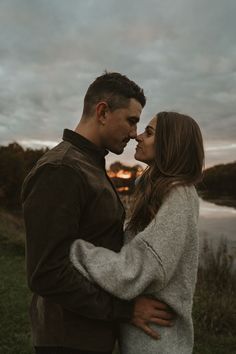 a man and woman standing next to each other in front of a body of water