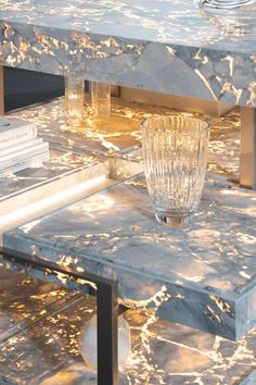 a marble coffee table with a glass vase on the top and some books in the background