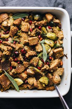 a casserole dish filled with stuffing, vegetables and herbs on a black surface