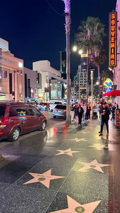 hollywood walk of fame star at night with people walking on sidewalk and cars driving down street