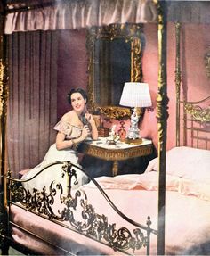 a woman sitting at a table in front of a bed with a mirror on it