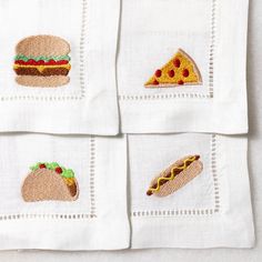 four embroidered napkins with different foods on them