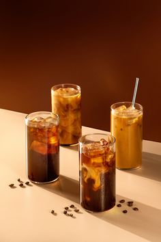 three glasses filled with drinks sitting on top of a table