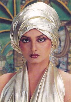 a woman wearing a white head scarf and gold dress with large earrings on her head