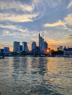 the sun is setting in front of some tall buildings on the water's edge