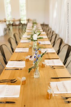 the long table is set with place settings and flowers in vases on each side