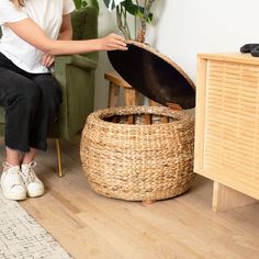 a woman sitting on a chair next to a wicker basket with an open lid