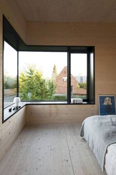 a bedroom with wooden walls and floor to ceiling windows looking out onto the countryside outside