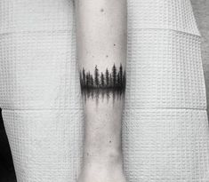 a person with a tattoo on their arm that has trees in the middle of it