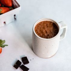 a cup of chocolate next to some strawberries