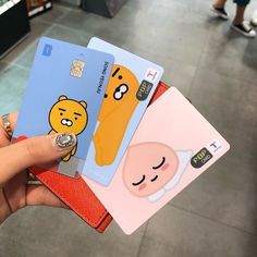 a person holding three credit cards in their hand, one with a bear on it