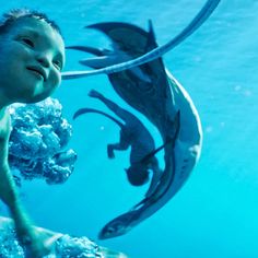 a young boy swimming in the water next to an underwater sculpture that looks like a fish