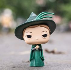 a close up of a toy figurine with a hat and green dress on