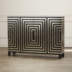 an art deco sideboard with black and gold lines on the front, against a white wall